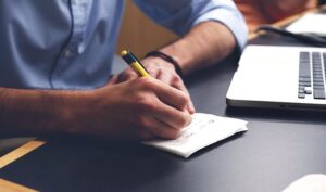 Flat‑lay workspace with laptop, notebook, and pen—environment of a small business owner writing product copy.